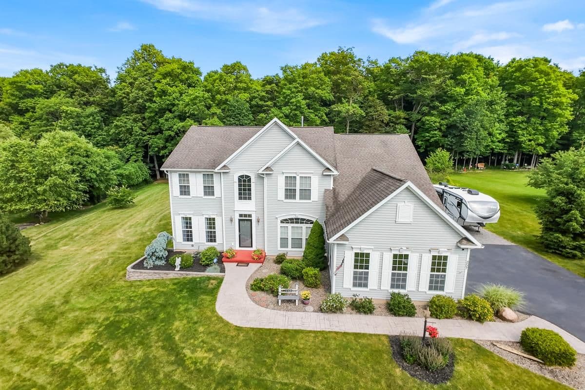 Aerial view of a two-story home on a large wooded lot
