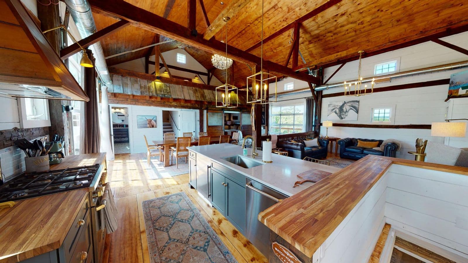 Great room of a renovated barn with exposed beams and a long kitchen island